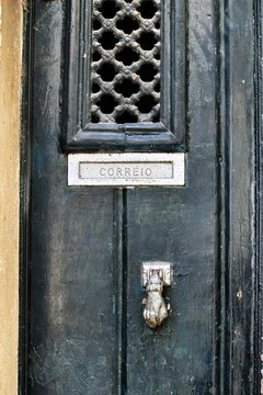 Green wooden door with door knocker hand shape.