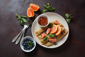 Sweet pancakes wrapped with fresh mint, strawberries, blueberries, oranges and jam. Healthy breakfast concept
