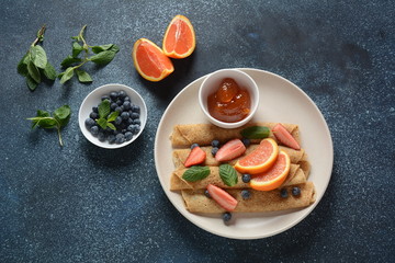 Sweet pancakes wrapped with fresh mint, strawberries, blueberries, oranges and jam. Healthy breakfast concept