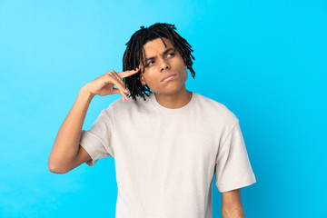 Young African American man over isolated blue background making the gesture of madness putting...