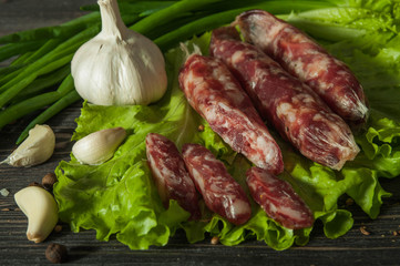 Sausage with garlic and herbs. On the brown table is a sausage with greens. Delicious country food. Delicious sausage with herbs and garlic.