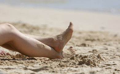 Feet of a girl on the sand of a beach.