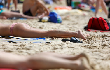 Fototapeta na wymiar A girl in a swimsuit sunbathes on the shore of a sea beach.