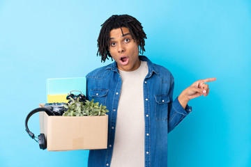 Young African American man making a move while picking up a box full of things surprised and...