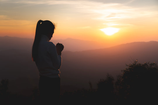 Silhouette of young  human hands  praying to god  at sunrise, Christian Religion concept background.