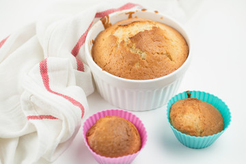 Summer seasonal Home pastries: a group of muffins in silicone shape and a cupcake in a large ceramic bowl. Decorated with cotton kitchen towel. White background, place for inscription