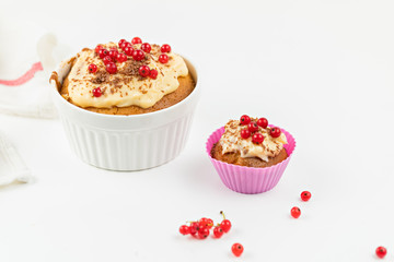 Summer seasonal Home pastries: cupcake in silicone shape is decorated with red currant berries and cream sauce. Maffins in pink individual form for baking.  berries against the background. 
