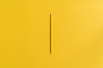 Yellow pencil on the yellow background. Top view of the pencil in the centre of the frame....