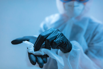 Medical doctor, scientist in full body suit for prevention from viruses and diseases holding a antiseptic tissue for disinfection.
