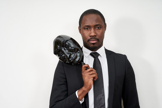 African Young Man Wearing Black Suit Taking Off Plastic Mask Revealing Face