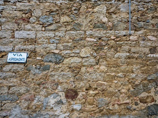 Typical and ancient stone wall of a Sardinian town with street sign 