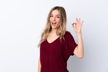 Young woman over isolated white background surprised and showing ok sign