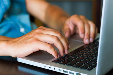 Close-up of young man using the laptop in his office connecting wifi.Businessman using laptop. Student is searching in Internet. wearing jeans shirt.