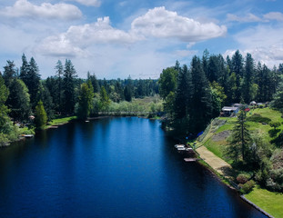 Lovely Lake Holm Water Access Site in springtime with the surrounding forest and homes and the sky and clouds in Auburn Washington