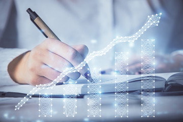 Multi exposure of woman's hands making notes with forex graph hologram. Concept stock market analysis.