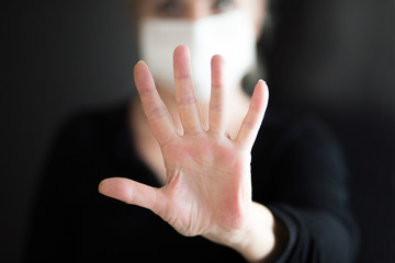 Senior woman wearing mask, shows clean hands and show stop hands. Selective focus.