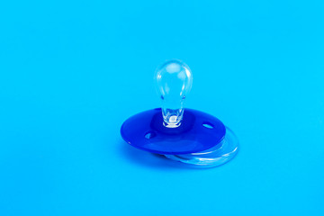 a round pacifier babies made of transparent soft latex, mock up plastic soother isolated on blue...