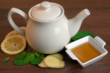 Close-up of ginger, mint, honey and lemon surrounding teapot