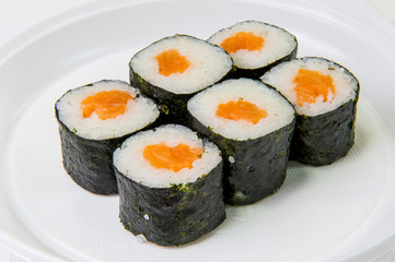 Traditional Japanese rolls of seaweed, rice and salmon on a plastic disposable plate on a white background
