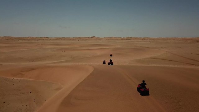 4K aerial drone video of quad bikers riding above along sand dunes near Swakopmund, Atlantic Ocean coastline, west coast yellow sandy landscape, Namib Desert panorama in Namibia, southern Africa