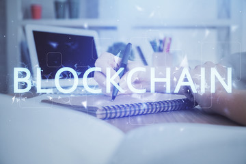 Cryptocurrency hologram over hands taking notes background. Concept of blockchain. Multi exposure