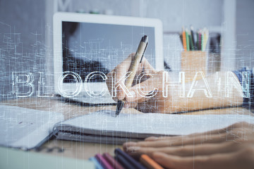 Cryptocurrency hologram, bitcoin, ico theme over hands taking notes background. Concept of...