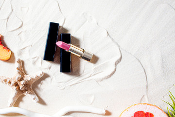 Wonderful beach. Lipstick, lip gloss, lip balm lie on the sand, surrounded by juicy fruits,...