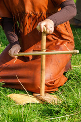 Woman make a fire with a bow drill