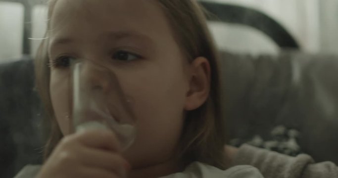 Zbliżenie chorej dziewczynki, k&oacute;ra robi nebulizację.