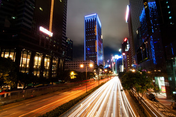 Fototapeta na wymiar Long exposure shot with trailing lights of busy traffic at night in Hong Kong with lighted skyscrapers in the background