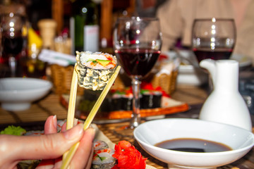 Girl holding Japanese dish roll with two sticks. Delicious mouth-watering Japanese cuisine in Europe.