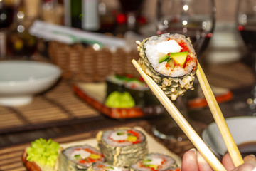 Girl holding Japanese dish roll with two sticks. Delicious mouth-watering Japanese cuisine in Europe.