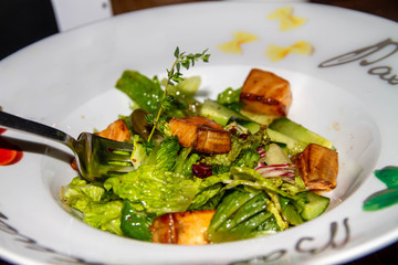 Salad of lettuce leaves, fish trout on a white plate. Fresh, tasty dish in the restaurant.
