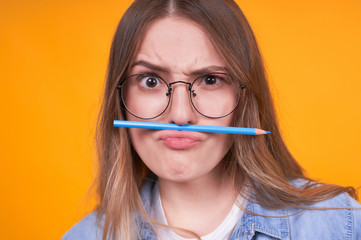 Cute funny girl looks straight in glasses and pencil like a mustache