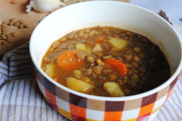 Vegan Lentil Soup with Vegetables served in a plaid bowl. Close up view.