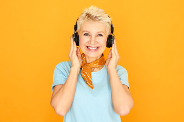 Modern stylish Caucasian woman pensioner with short hairstyle relaxing listening to favorite tracks...