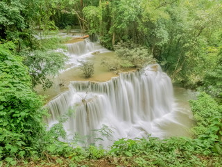 Fototapeta na wymiar view of silky waterfall flowing on the cliff around with green forest background, Chat Kaew (floor 4th), Huai Mae Khamin Waterfall, Kanchanaburi, west of Thailand.