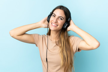 Young caucasian woman isolated on pink background listening music