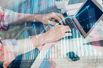 Double exposure of stock graph with businessman typing on computer in office on background. Concept...