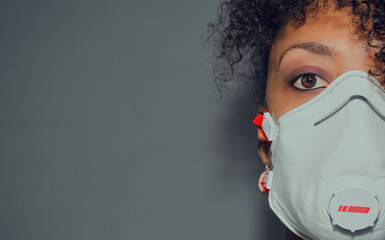 Half face of a black woman wearing a FFP3 mask with exhalation valve during Coronavirus crisis. ...