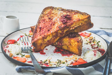 French toast stuffed with cream cheese, served with berry coulis, fresh strawberries and cookie crumble