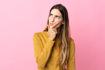 Young caucasian woman isolated on pink background having doubts