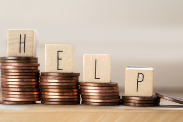 Wooden cubes with the word Help and pile of coins, money stairs, business concept