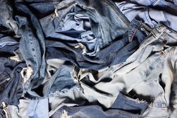 Different blue colored female jeans mixed, messy pile of navy jeans. Textile consumerism, many clothes are not used