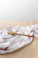 Maca root powder in a wooden spoon on top on a white cloth, soft light and wooden table background