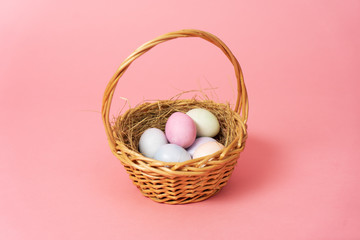 Happy easter: basket with colorful eggs on a pink background.