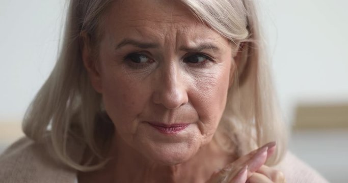 Close up head shot unhappy anxious middle aged woman having bad premonitions, worrying about health problems. Upset thoughtful older female retiree suffering from dementia alzheimer disease.