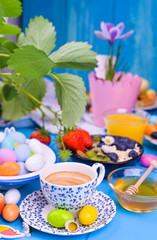 Easter breakfast. Fresh aromatic espresso coffee and easter colored eggs on a blue wooden background. Muesli, strawberries for breakfast.