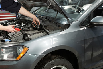 Obraz na płótnie Canvas Auto mechanic check car battery voltage by voltmeter multimeter at repair service station