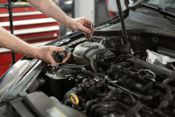 Hand of Mechanic technician service check antifreeze coolant fluid in garage